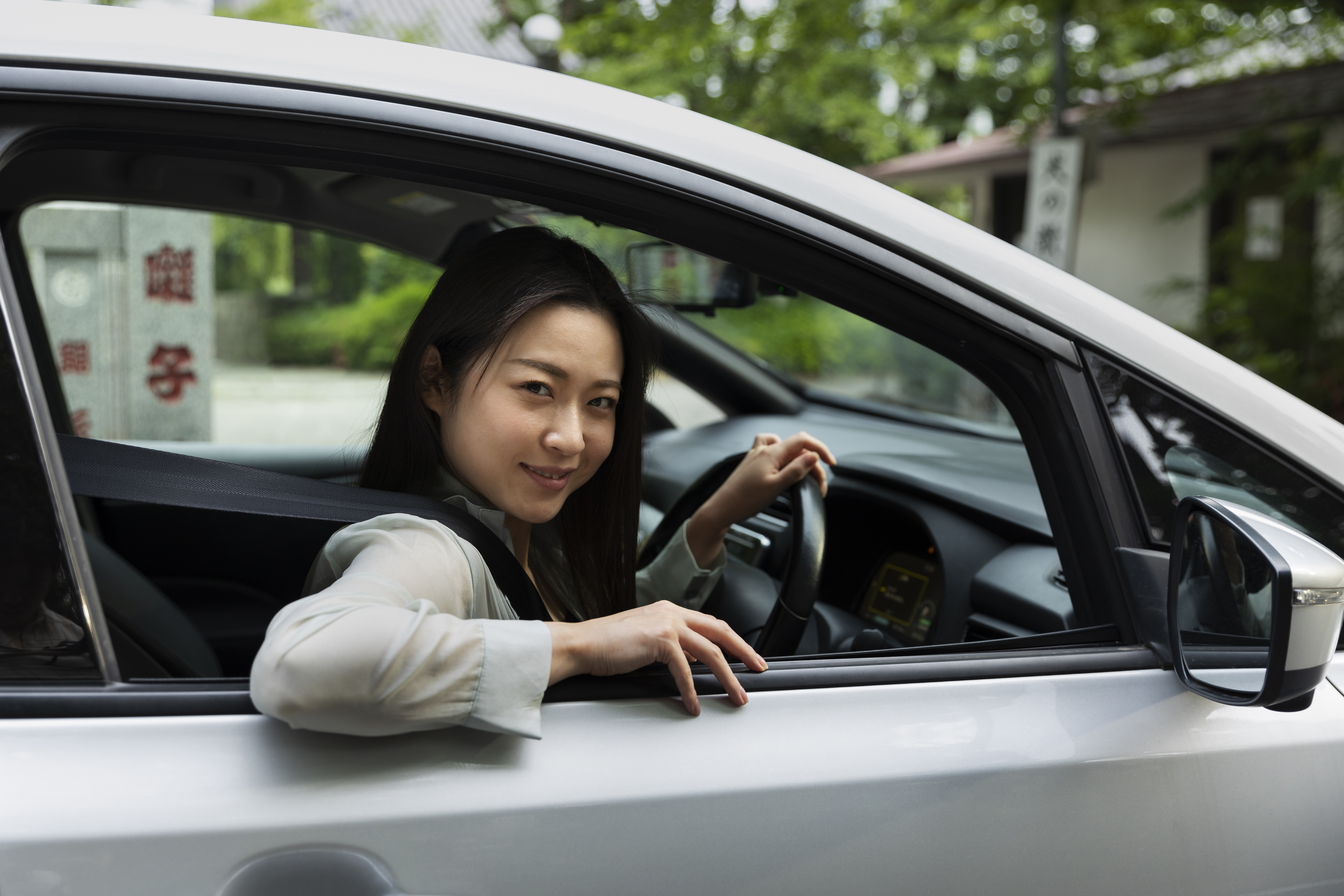 一位女性坐在车内，透过车窗微笑看向前方，神情轻松愉快。她即将离开繁忙的城市，踏上回家的旅程，脸上流露出对团圆与新年的期待，画面传达出自由、安心与回家过年的喜悦感受。