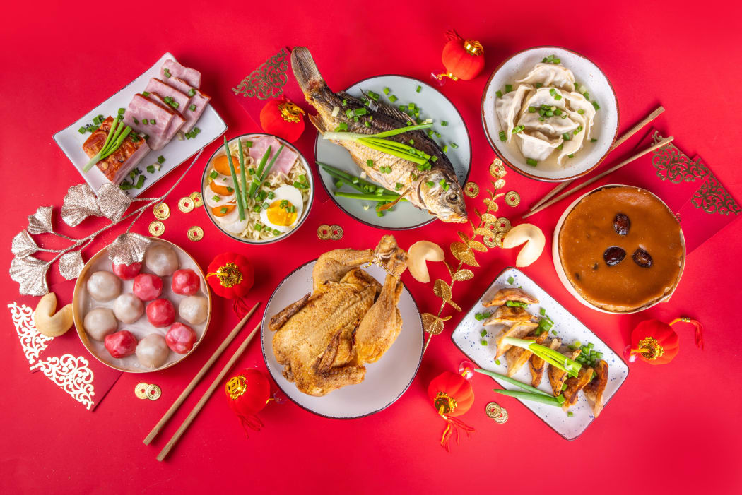 丰盛的年夜饭菜肴,有整鸡、鱼、饺子和红色装饰物
